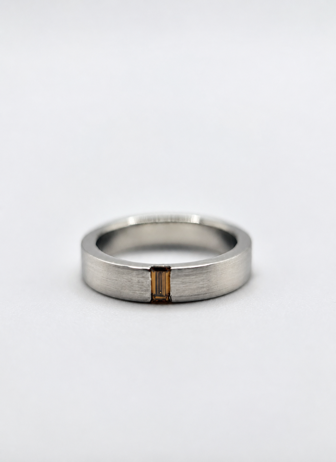 men's platinum wedding band with a baguette-cut champagne diamond set flush — understated and architectural